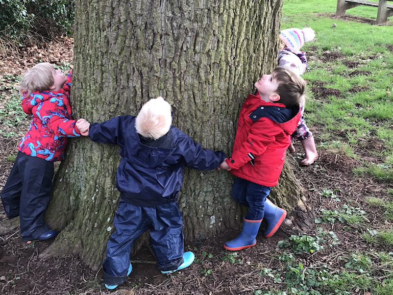 Nursery children hugging a tree